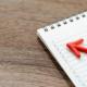 Image of a notebook with a calendar on a wooden table with a red arrow pointing to the dates