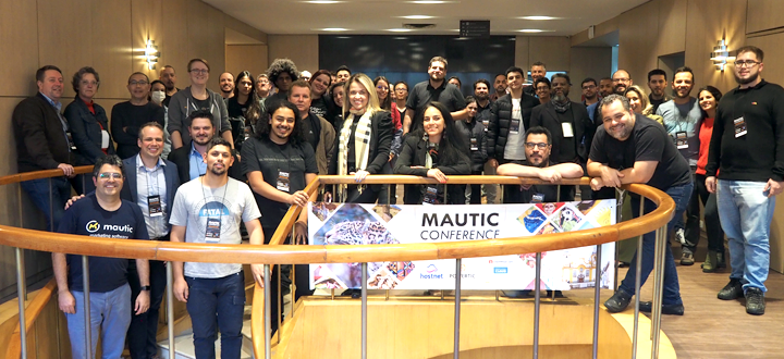 Photo of attendees behind a Mauticon banner, standing in a stairwell at the conference venue.