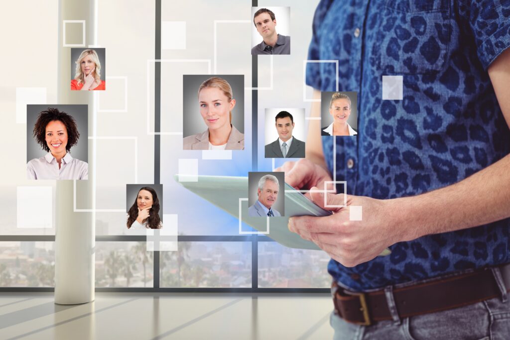 An image of a white man wearing a dark blue short sleeved shirt and holding an ipad with images of different people connected with white squares showing superimposed on top of the photograph.