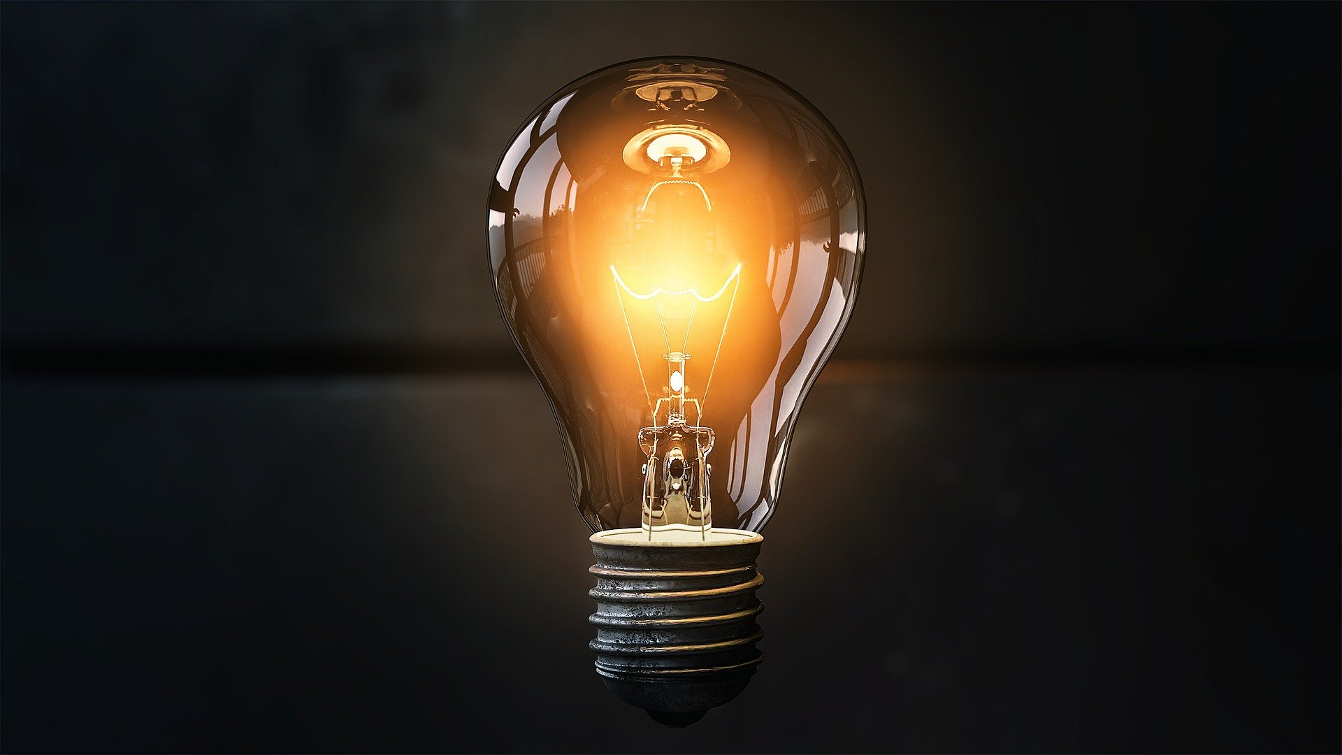 Photo of a lightbulb illuminated against a dark background.