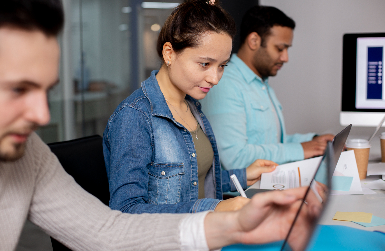 Photo of three people working at computers and analysing data.