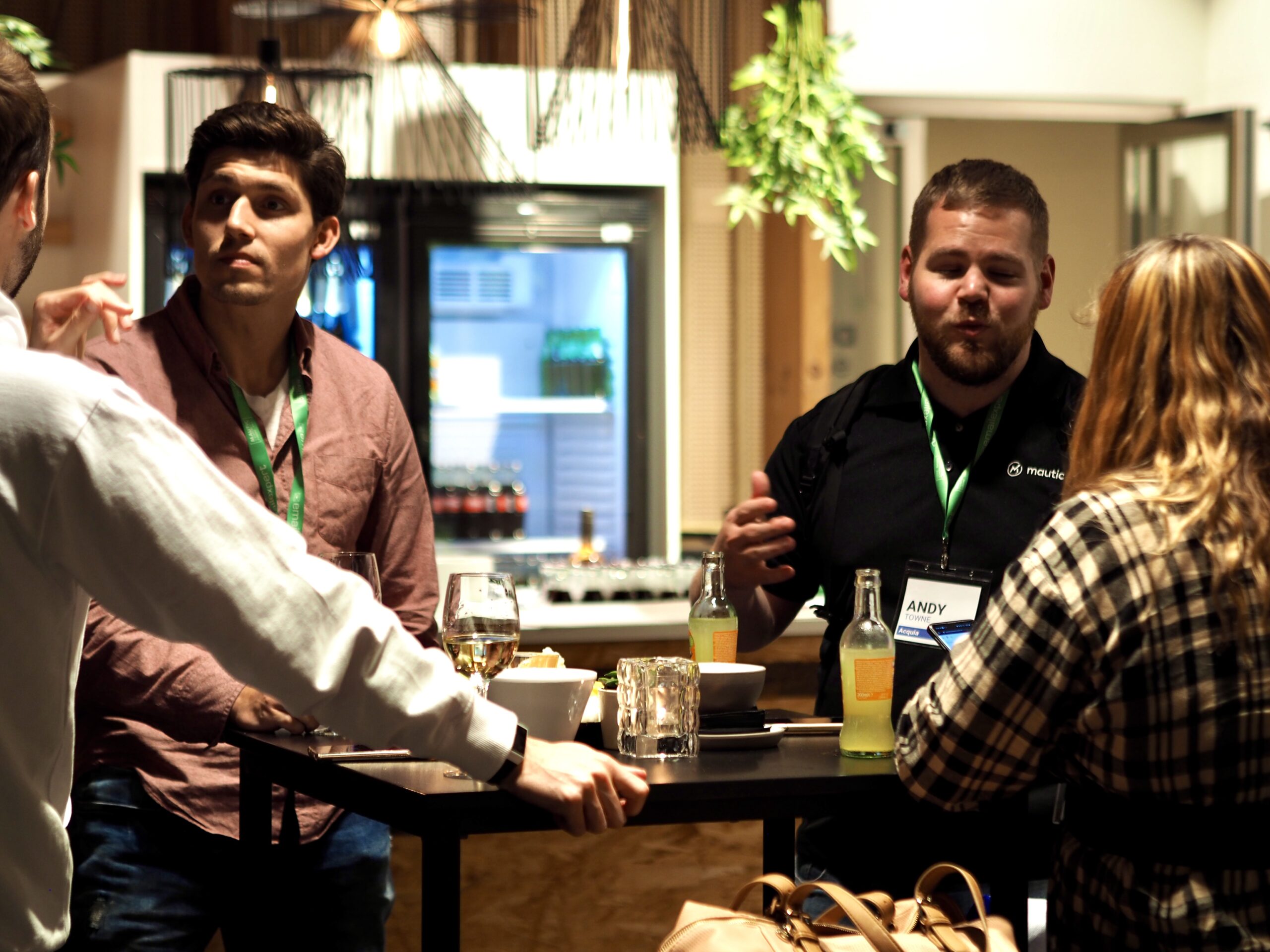 Photo of four people standing around a table at a conference talking.