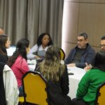 Photo of a diverse group of people sitting around a table collaborating on a project.