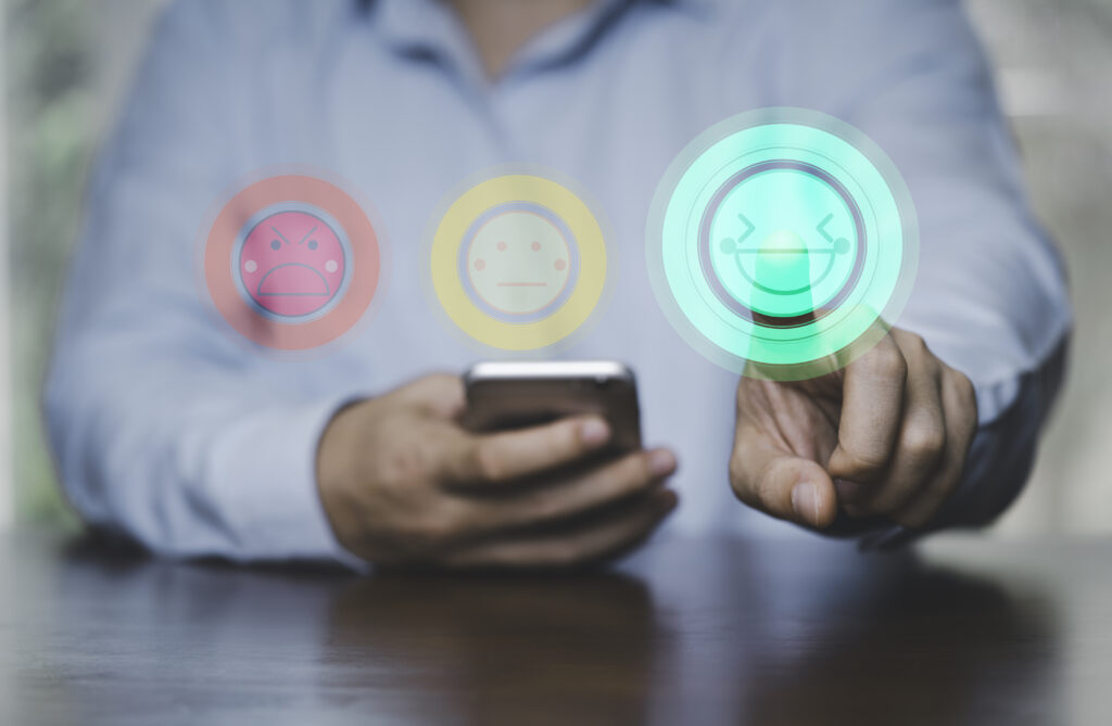 Businessman holding smartphone and touching to smile face icon showing customer satisfaction.