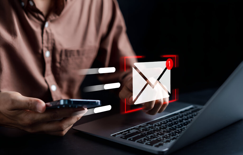 Businessman at a laptop with a hologram email icon which looks to be moving