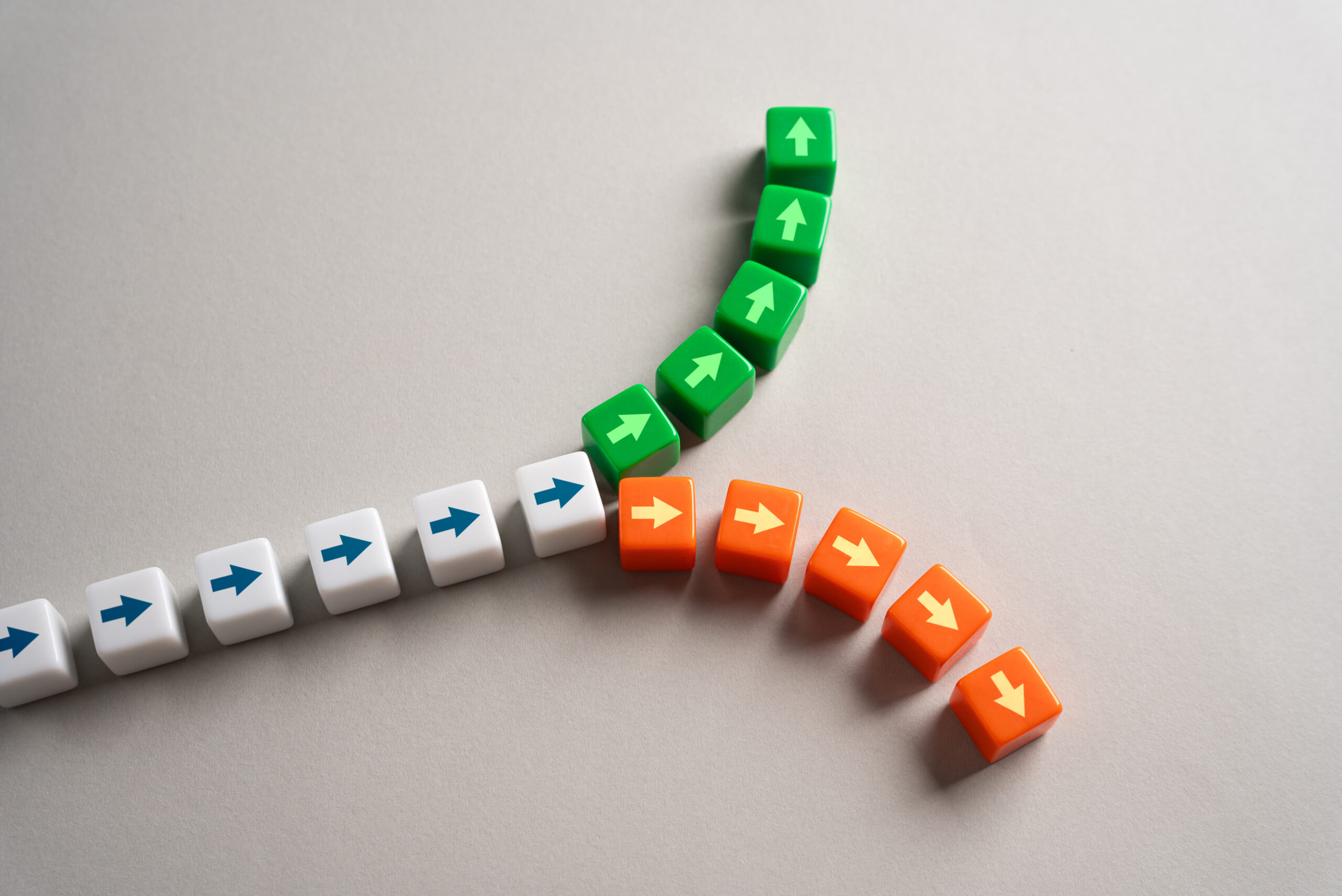 A fork of coloured dice with arrows on them, starting white and then dividing a path into two opposite directions, the upward being green and the downward being red.