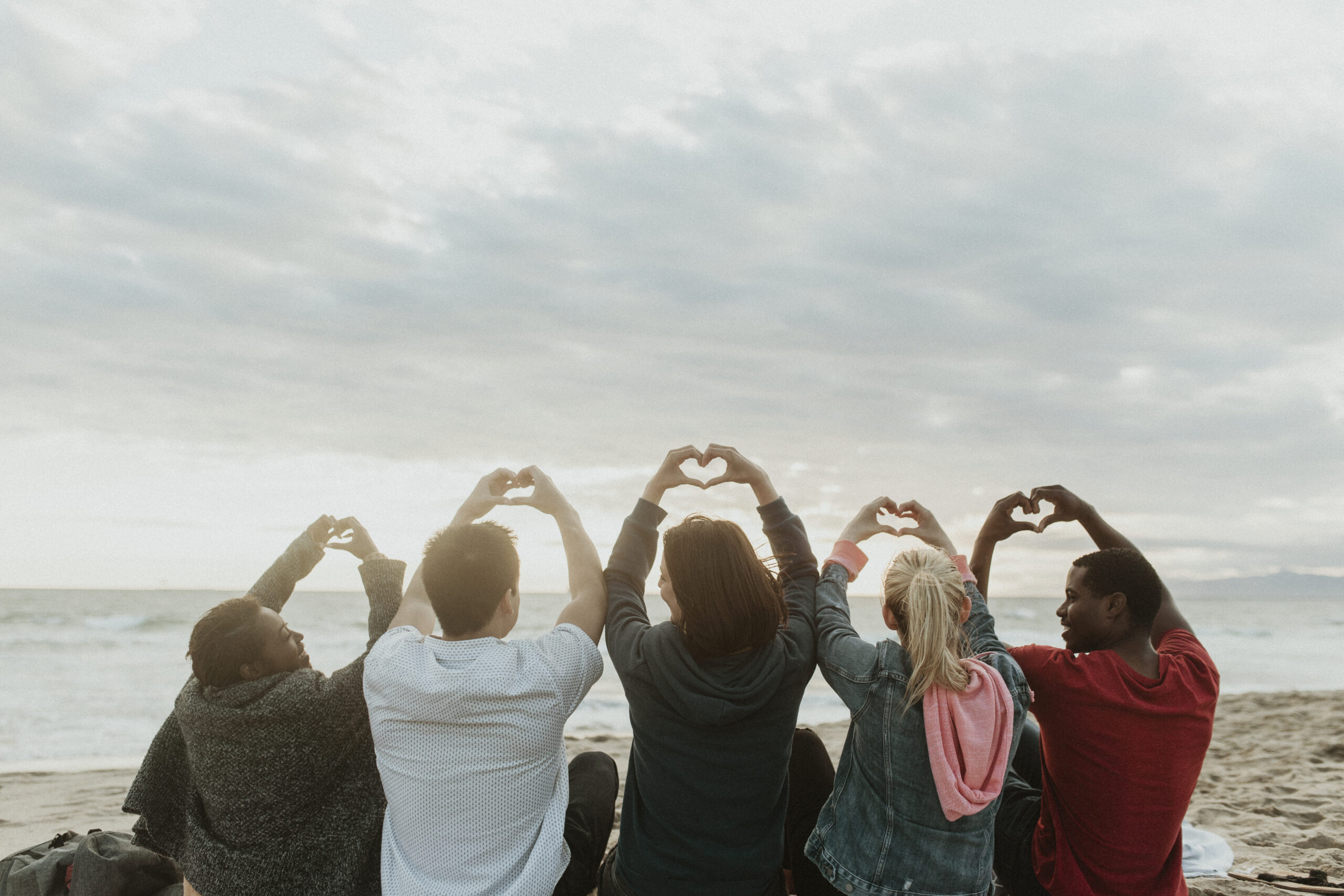 Friends making love heart hands at the beach