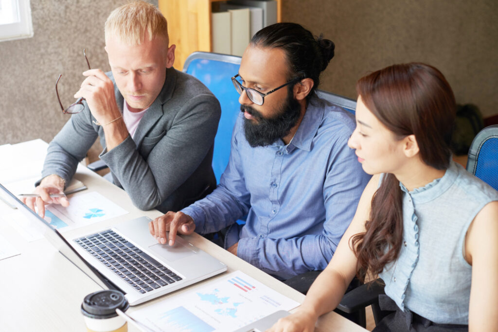 Photo of three people sitting together around a laptop.