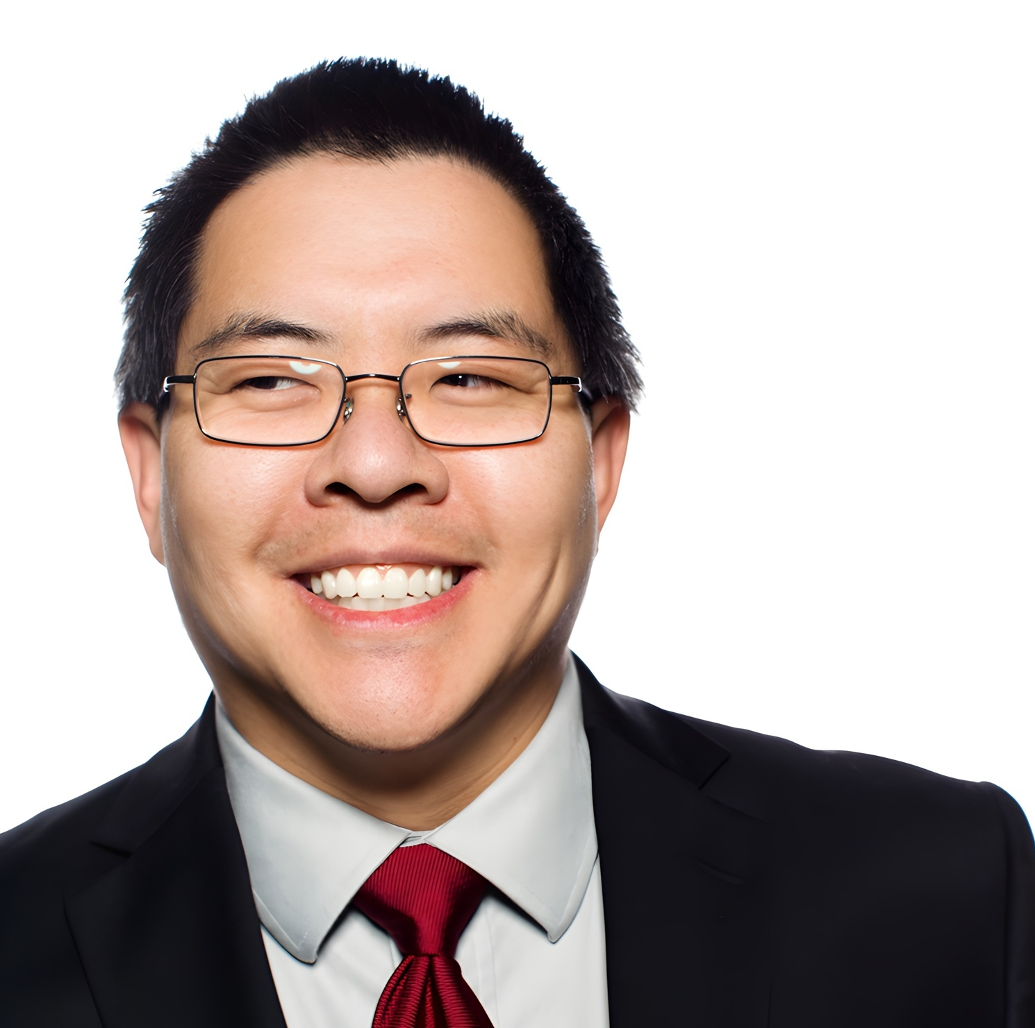 Photo of an asian man wearing glasses with short dark hair. He's wearing a dark black suit with a pale collared shirt and a red tie.