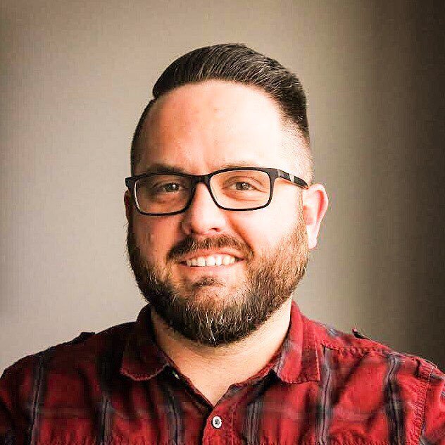 Photo of a white man with short hair and a full face beard and moustache.