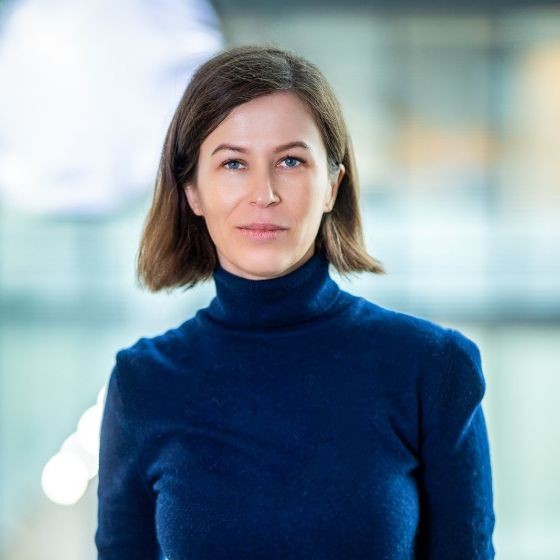 Photo of a woman with shoulder-length dark hair wearing a dark blue polar neck jumper.