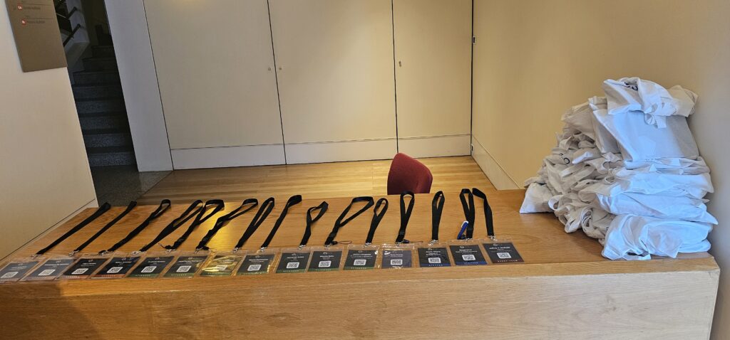 Photo of lanyards laid out on a bench with swag bags piled alongside.