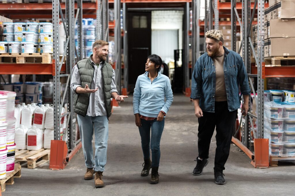 Two men and a woman walking through a warehouse chatting.