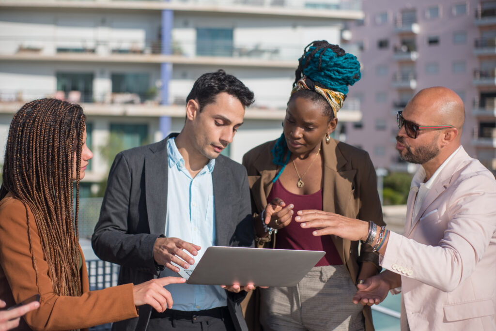 Photo of business people discussing matters on terrace roof. Men and women of different nationalities on terrace roof, using laptop