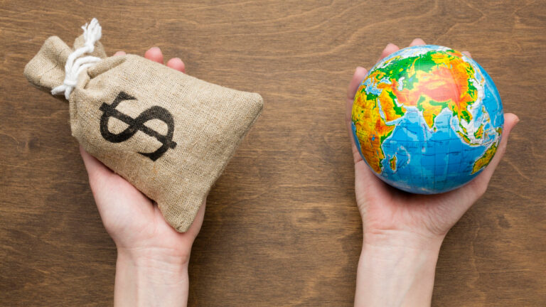 Photo of two hands, one holding a bag of money with a $ symbol on it, the other holding a globe.